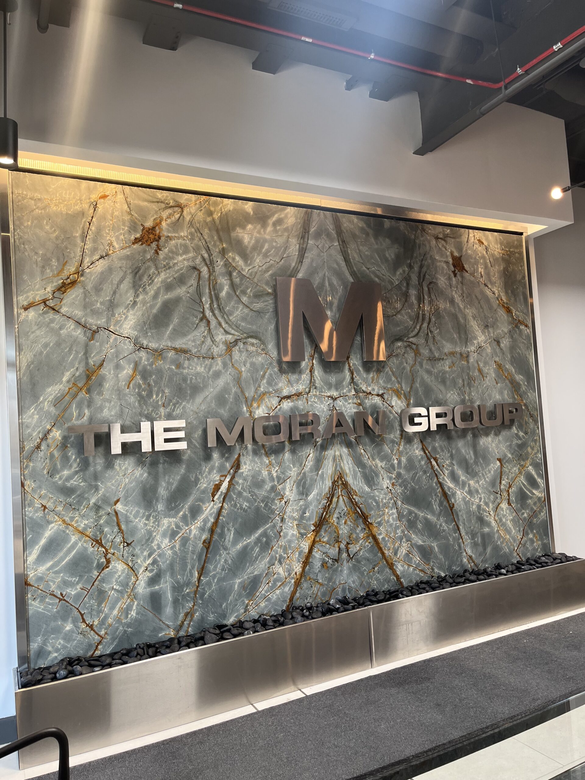Granite Tile Water Wall featuring etched logo for FE Moran, enhancing the interior design of a commercial space in Northbrook, Illinois.